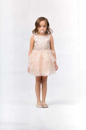 Portrait of happy pretty curly little girl standing and posing over white backgroundの写真素材
