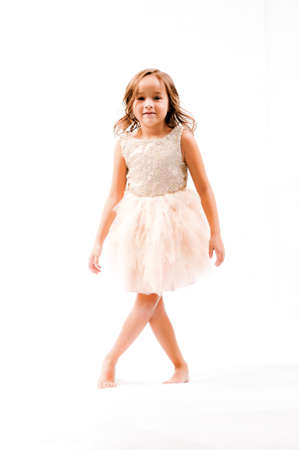 Portrait of happy pretty curly little girl standing and posing over white backgroundの写真素材