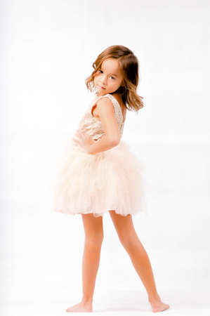 Portrait of happy pretty curly little girl standing and posing over white backgroundの写真素材