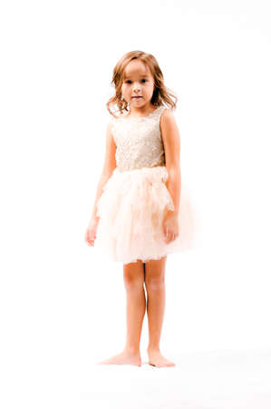 Portrait of happy pretty curly little girl standing and posing over white backgroundの写真素材