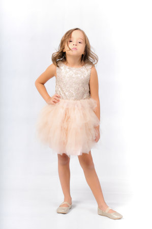 Portrait of happy pretty curly little girl standing and posing over white backgroundの写真素材