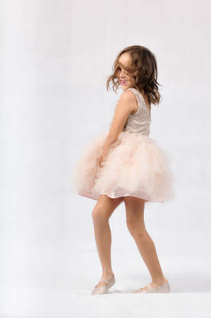 Portrait of happy pretty curly little girl standing and posing over white backgroundの写真素材