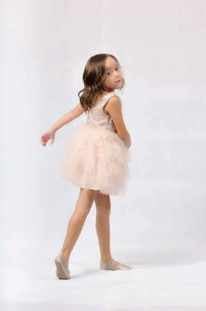 Portrait of happy pretty curly little girl standing and posing over white backgroundの写真素材