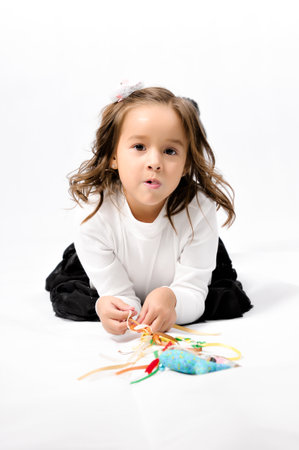 Portrait of happy pretty curly little girl wear Santa Claus dress and posing with Christmas decoration over white backgroundの写真素材
