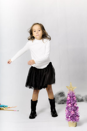 Portrait of happy pretty curly little girl wear Santa Claus dress and posing with Christmas decoration over white backgroundの写真素材