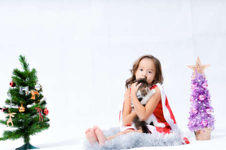 Portrait of happy pretty curly little girl wear Santa Claus dress and posing with Christmas decoration over white backgroundの写真素材