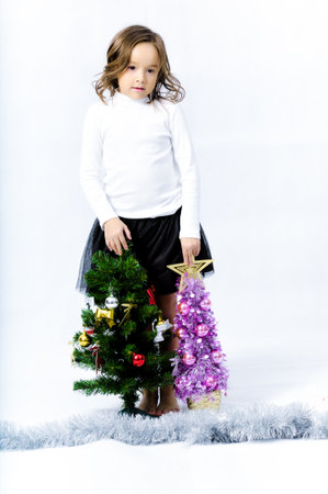 Portrait of happy pretty curly little girl wear Santa Claus dress and posing with Christmas decoration over white backgroundの写真素材