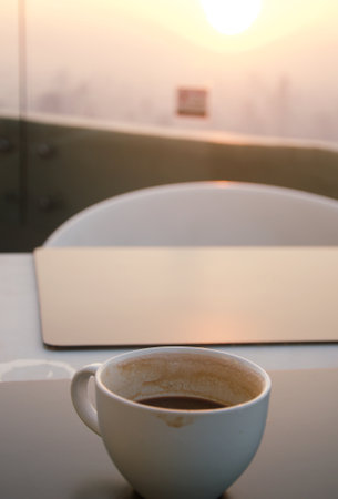 Coffee cup on table in coffee shop at sunset, stock photoの写真素材