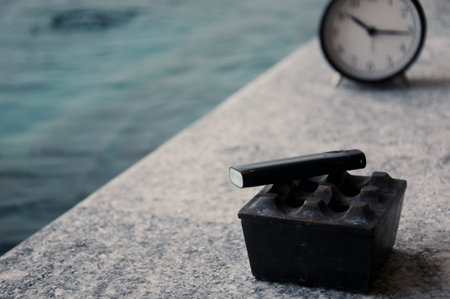Close up of an alarm clock on a pier by the sea.の写真素材