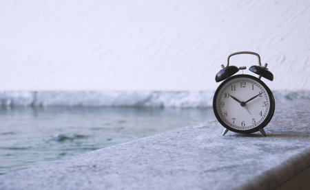 Alarm clock on the edge of a swimming pool on a rainy dayの写真素材