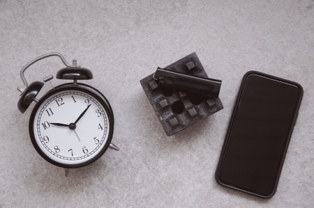 Alarm clock, mobile phone and bricks on a gray background.の写真素材