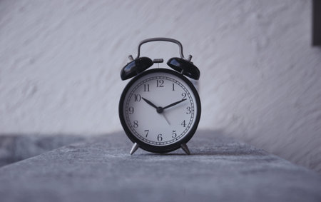 Retro alarm clock on the background of a white wall. Time concept