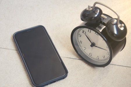 Black alarm clock and smartphone on the floor. Time management concept.の写真素材