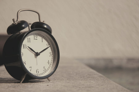 Black alarm clock on concrete background with copy space. Time concept.
