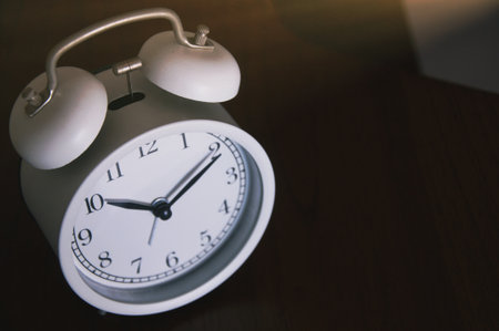 White alarm clock on the table. The concept of time management.の写真素材