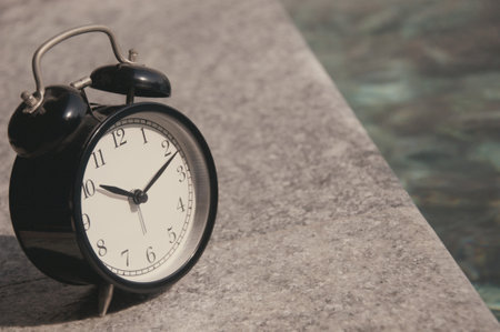Retro alarm clock on a swimming pool background. Selective focus.の写真素材