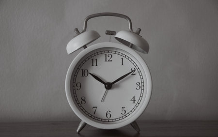 White alarm clock on gray wall background. Time concept. Close up.の写真素材