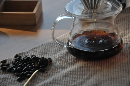 Coffee in glass teapot and coffee beans on tableの写真素材