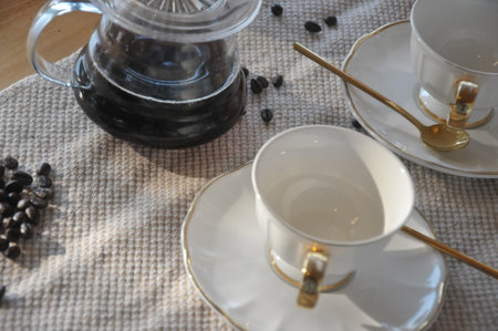 Coffee pot and cup of coffee on the table with coffee beansの写真素材