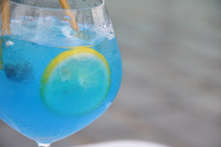 Blue cocktail with lemon and ice on a terrace in a restaurantの写真素材