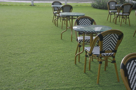 Tables and chairs in the green grass at the park in the evening.の写真素材