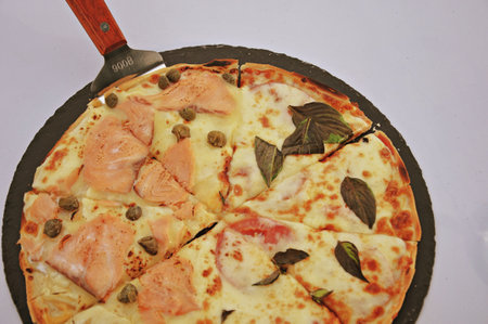 Pizza with salmon, mushrooms and olives on a black plateの写真素材