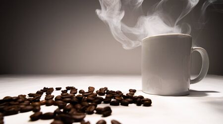 White coffee mug smoke coming out of the coffee cup. And coffee beansの写真素材