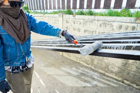 Worker painting steel tube with paint rollerの写真素材