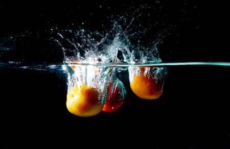drop Many tomatoes in tank. water is splash on black backgroundの写真素材