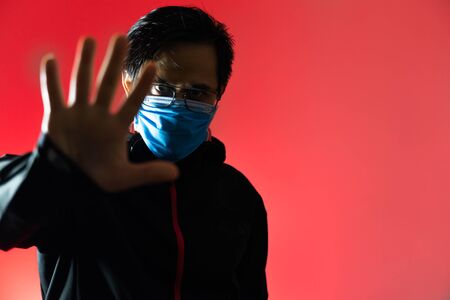 Asian man wearing a hood and mask Make a hand signal to stop because Afraid of Covid 19の写真素材