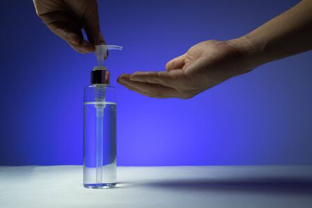 Use your hands to press the alcohol gel In the pump bottles for sterilize In the blue backgroundの写真素材