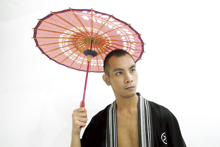 Young man holding a red umberllaの写真素材