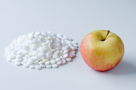Fresh juicy apple versus a pile of pillsの写真素材