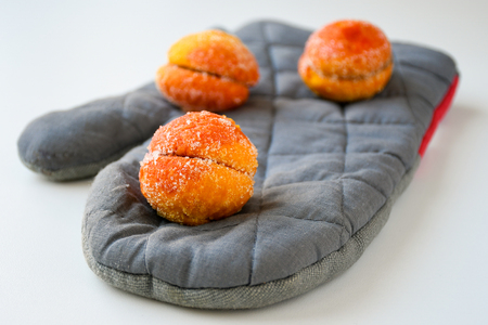 Freshly made sweet apricots with sugar coating sitting on a grey baking gloveの写真素材