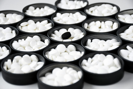 Group of white pills with one black pillの写真素材