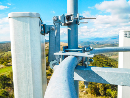 Mobile telephone network base station telecommunication tower with smart cellular antennas radiating and broadcasting strong digital signal waves from view from the topの写真素材