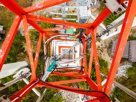 Mobile telephone network base station telecommunication tower with smart cellular antennas radiating and broadcasting strong digital signal waves from view from the topの写真素材
