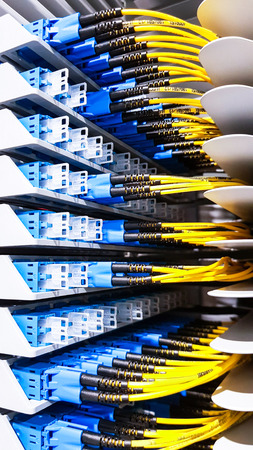 Colorful high speed optical fiber cables connected to the cloud network servers equipment switch inside modern big data center roomの写真素材