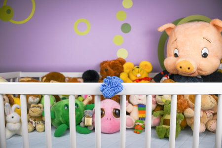 Group of colorful fluffy stuffed animal toys close up looking at blue small baby shoe in a crib