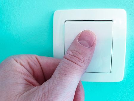 Switch off and on the light with finger close up on a blue turquoise wall