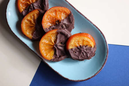 Candied orange slices in chocolate, served on a blue plate.の写真素材