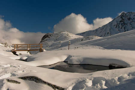 Bridge over a mountain stream in winter. Winter mountain landscape. January in the Valley of Five Ponds in the Tatra Mountains. Blue sky over the valley.の写真素材