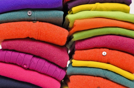 Stack of women's sweaters and cardigans in bright vivid colours against white.の写真素材