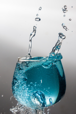 Blue water splash in a wine glassの写真素材