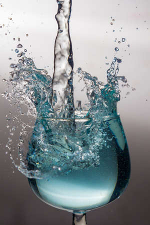Blue water splash in a wine glassの写真素材