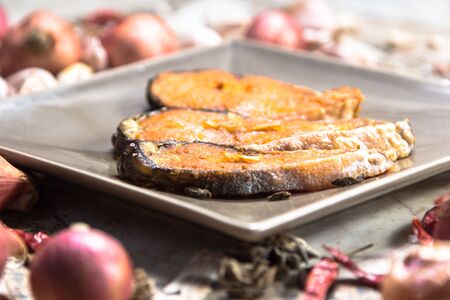 Fried fish on a plate with spicesの写真素材