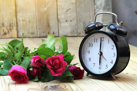 Alarm clock with roses on old wood.の写真素材
