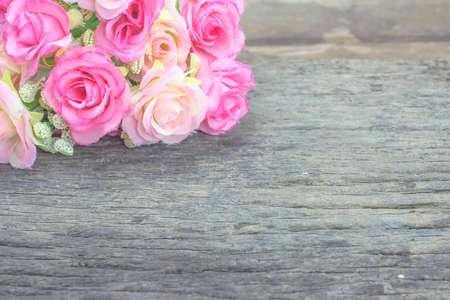 Artificial roses on a wooden floor. Work space.の写真素材