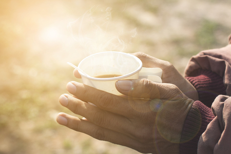 Good morning coffee in a paper cup in the hands of men in winter.の写真素材