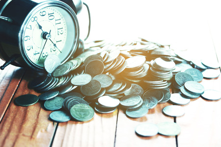 Silver Coin with Retro Alarm Clock on Wooden Table.の写真素材